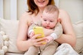 A mother woman shows a mobile phone to an infant baby boy. Mom and son look at the smartphone screen Royalty Free Stock Photo