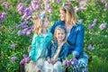 Mother woman with two cute smiling girls sisters lovely together on a lilac field bush all wearing stylish dresses and Royalty Free Stock Photo