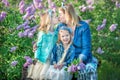 Mother woman with two cute smiling girls sisters lovely together on a lilac field bush all wearing stylish dresses and Royalty Free Stock Photo