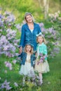 Mother woman with two cute smiling girls sisters lovely together on a lilac field bush all wearing stylish dresses and Royalty Free Stock Photo