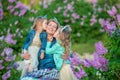 Mother woman with two cute smiling girls sisters lovely together on a lilac field bush all wearing stylish dresses and Royalty Free Stock Photo