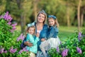 Mother woman with two cute smiling girls sisters lovely together on a lilac field bush all wearing stylish dresses and Royalty Free Stock Photo
