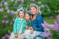 Mother woman with two cute smiling girls sisters lovely together on a lilac field bush all wearing stylish dresses and Royalty Free Stock Photo