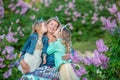 Mother woman with two cute smiling girls sisters lovely together on a lilac field bush all wearing stylish dresses and Royalty Free Stock Photo