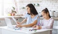 Mother working from home while daughter doing homework in kitchen Royalty Free Stock Photo
