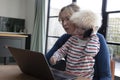 A mother working from home at a laptop computer with her young son on her lap Royalty Free Stock Photo