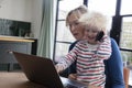 A mother working from home at a laptop computer with her young son on her lap Royalty Free Stock Photo