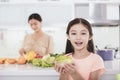 Mother working at kitchen and daughter showing health food