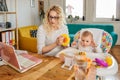 Mother working on laptop at home office with her baby Royalty Free Stock Photo