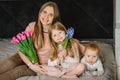 Mothers day concept. Cute little girl and boy greeting mother and gives her a bouquet of flowers tulips at home. Mom and Royalty Free Stock Photo