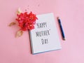 Mother's day greeting written on note book with flower and pen isolated on pink background. Royalty Free Stock Photo