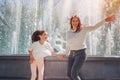 Mother& x27;s day. Young mother and her daughter having fun by fountain in summer park. Family jumping and laughing