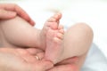 The mother& x27;s hands tenderly and lovingly hold the legs of a small child who is several months old from the moment of Royalty Free Stock Photo