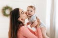 Mother& x27;s love. Happy mother holding her child in hands and kissing in cheek while playing and enjoying time with kid Royalty Free Stock Photo