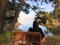 A mother and young daughter sitting side by side on a bench overlooking the ocean on a beautiful evening in the gulf islands