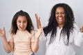 Mother and young daughter standing over white background celebrating crazy and amazed for success with arms raised and open eyes Royalty Free Stock Photo