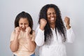 Mother and young daughter standing over white background excited for success with arms raised and eyes closed celebrating victory Royalty Free Stock Photo