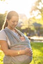 Motherhood, care, infants, summer, parenting concept - Young beautiful mom with a newborn baby in a sling walks and Royalty Free Stock Photo