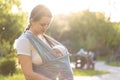 Motherhood, care, infants, summer, parenting concept - Young beautiful mom with a newborn baby in a sling walks and Royalty Free Stock Photo