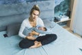 Motherhood and parenthood concept. Caucasian blond mother looking at camera, sitting on bed in her modern bedroom, and Royalty Free Stock Photo