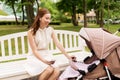 Happy mother with smartphone and stroller at park Royalty Free Stock Photo