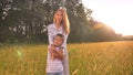 Mothering hug of asian female of her happy son, standing on the wheat field on sunrise