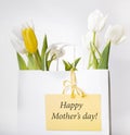 Festive white, yellow tulips composition, handmade heart, ribbon on white background. Bouquet of spring flowers in white paper bag Royalty Free Stock Photo