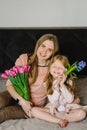 Mothers day concept. Cute little girl greeting mother and gives her a bouquet of flowers tulips at home. Mom and Royalty Free Stock Photo