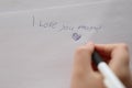 Mothers day holiday.moms day. I love you mom inscription on a white sheet and a heart and a childs hand with a pen Royalty Free Stock Photo