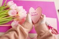 Mothers Day.I love you, Mom. Childrens hands holding a heart card.Pink heart card and pink tulips.child makes a card for Royalty Free Stock Photo