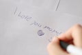 Mothers day . I love you mom inscription on a white sheet and a heart and a childs hand with a pen. Royalty Free Stock Photo
