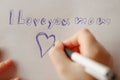 Mothers day.moms day.I love you mom inscription on a white sheet and a heart and a childs hand with a pen. Royalty Free Stock Photo