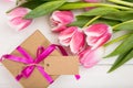 Mothers day. Pink tulips and a blank card gift on white background, top view, copy space Royalty Free Stock Photo