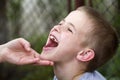 Mothers hand lovingly holding chin of small smiling handsome boy showing his white funny child teeth outdoors on blurred backgroun Royalty Free Stock Photo