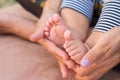 The mothers hands holds baby legs. Newborn foots