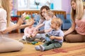 Mothers and their children together in club. Babies play with musical toys Royalty Free Stock Photo