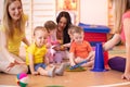 Mothers and their children together in gym. Babies playing with sportive equipment