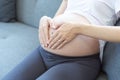 Mothers wearing wedding rings are making heart-shaped hands on their pregnant belly Royalty Free Stock Photo