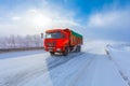 Motion blur of a red dump truck with cargo on winter road. Royalty Free Stock Photo