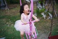 Motion blur shot of adorable toddler girl in pink ballet costume sit on the swing and laughing smile that shows happiness life of Royalty Free Stock Photo