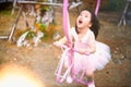 Motion blur shot of adorable toddler girl in pink ballet costume sit on the swing and laughing smile that shows happiness life of Royalty Free Stock Photo