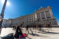 Motion blured people walking around a Harp street musician performing in front of Palacio Real Royal palace