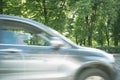 Motion blurred fast moving car. Background of green trees