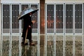 Old man with umbrella and cane walking in the rain