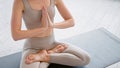 Motion past lady yoga practitioner in new beige tracksuit sitting in lotus position with namaste on mat in light studio