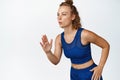 Motion portrait of young sportswoman running in sportsbra and shorts. Active fitness woman jogging, run and control