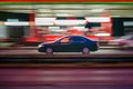 Motion shot of a black car driving fast down a road near an illuminated gas station Royalty Free Stock Photo