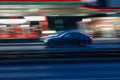 Motion shot of a black car driving fast down a road near an illuminated gas station Royalty Free Stock Photo