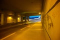 A motioned blurred motor scooter travels along a city underpass at night