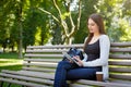 Motivated asian freelancer in the park. Girl on a bench, drinking coffee and working with tablet